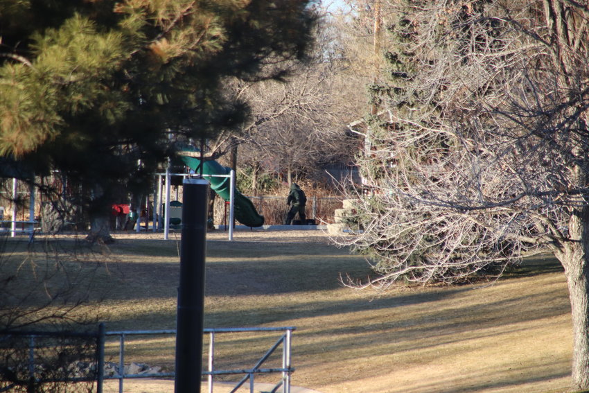 A bomb squad technician retrieves a package from Rotolo Park's playground on Jan. 20. The package was later found to be non-explosive.